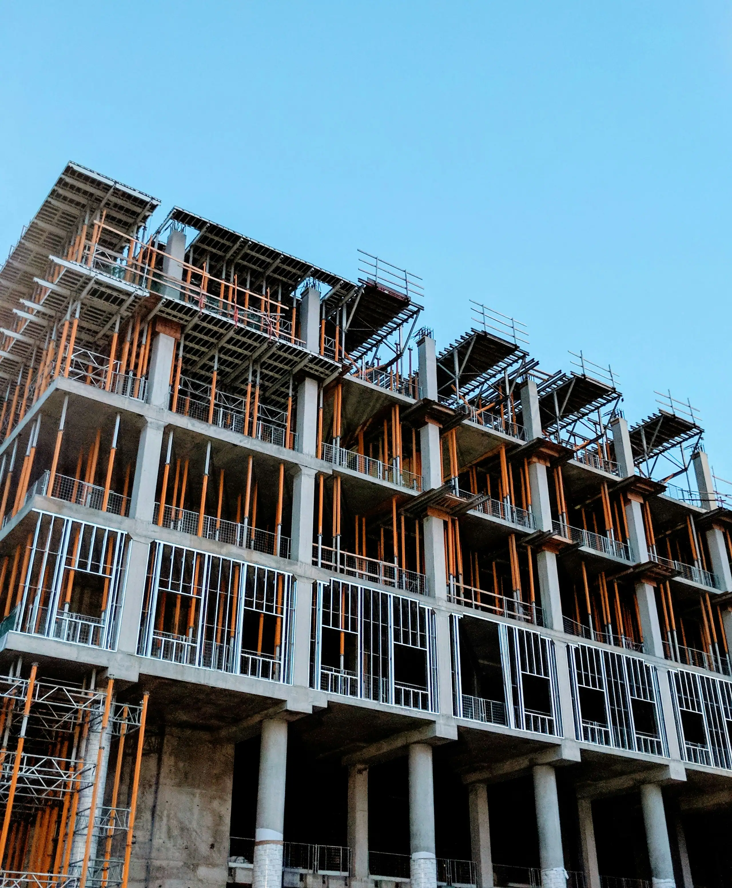 A concrete-framed building under construction against a clear sky