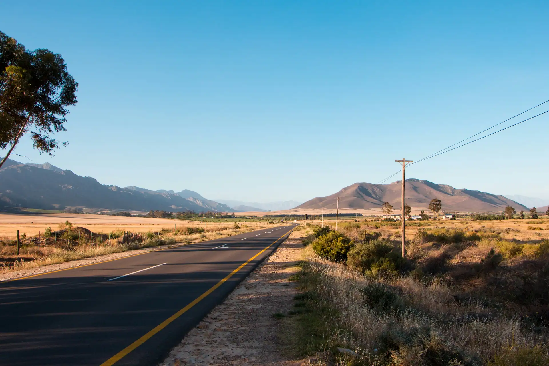 A sealed road running across dry plains toward hills